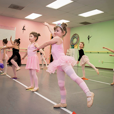 Young ballet students wearing pink tutus, practicing in the studio