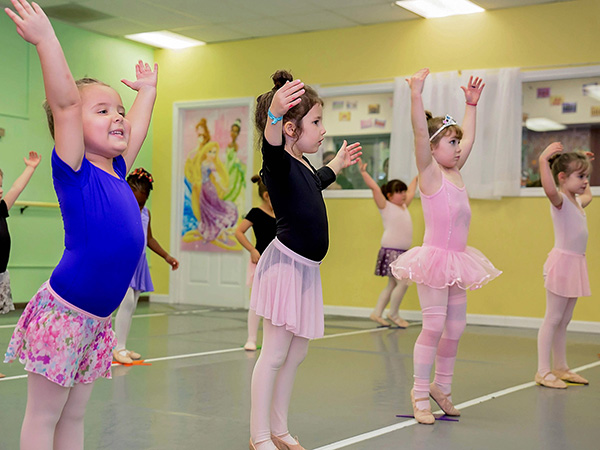 little girls dance class with arms up and on tippy toes